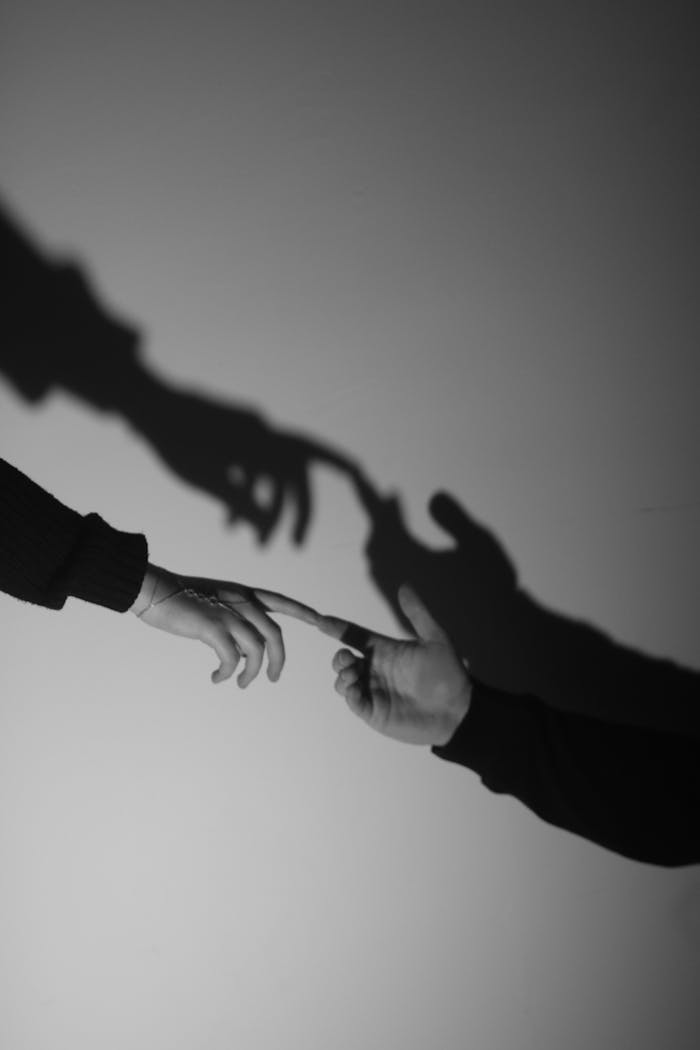 Artistic black and white photo of two hands reaching towards each other, highlighting connection and touch.