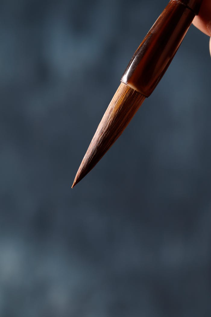 Detailed close-up of an artist's paintbrush tip on a blurred blue background.